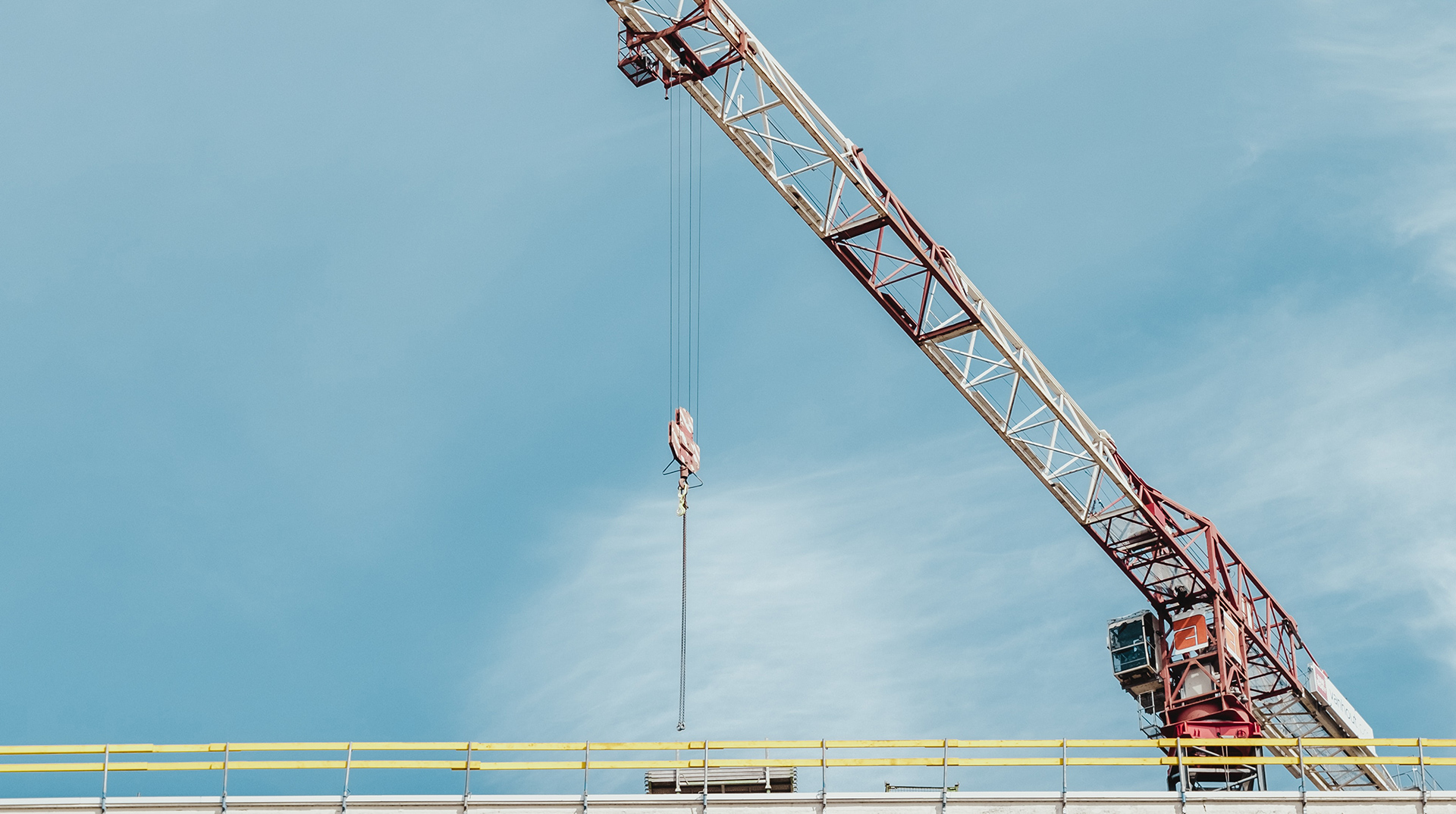 Großer Kran auf einer Baustelle bringt Material aufs Dach