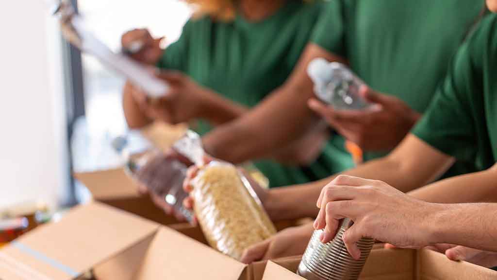 Ehrenamtliche Helferinnen und Helfer packen Lebensmittel in Kisten