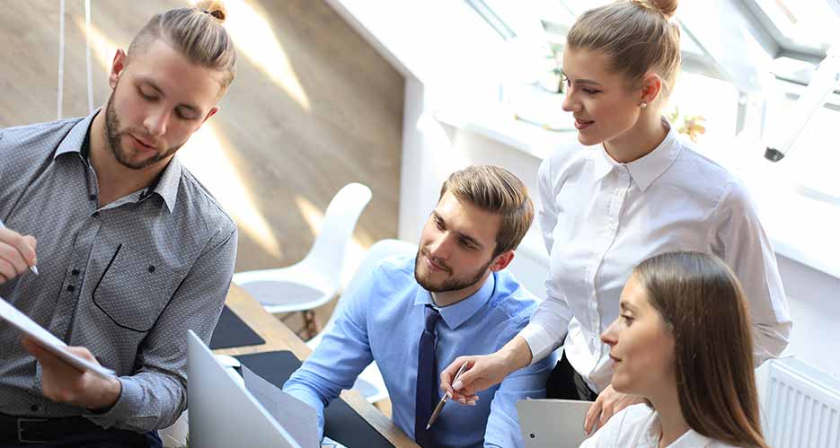 Foto eines kleinen Teams von vier MItarbeitenden im Büro