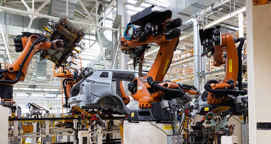 Die neue EU-Maschinenverordnung Große Maschinen in einer Fahrzeug Fertigungsanlage arbeiten an einer Karosserie